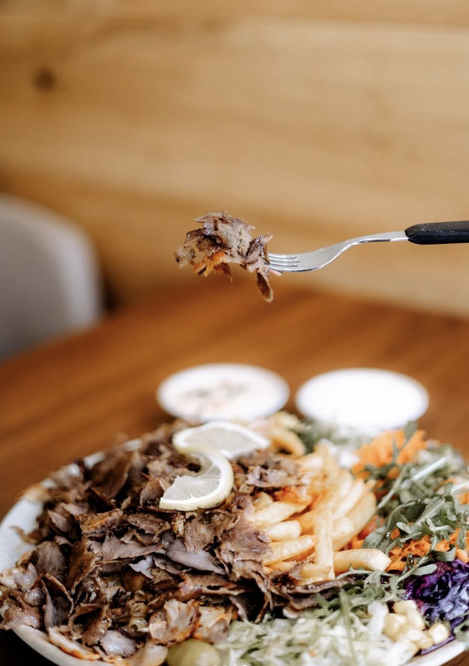 Erster Bissen vom Döner-Teller mit Zitrone und Soßen